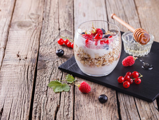 Breakfast with muesli, yogurt,honey and fresh berries in a glass on a wooden background. selective focus