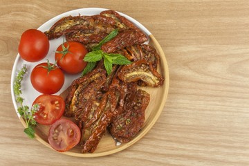 Spicy dried tomatoes marinated in olive oil. Delicious delicacy. Refreshments at the party. Sun-dried tomatoes with olive oil, background. Healthy food.
