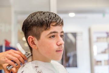 teenage boy sitting at the hairdresser salon for a haircut
