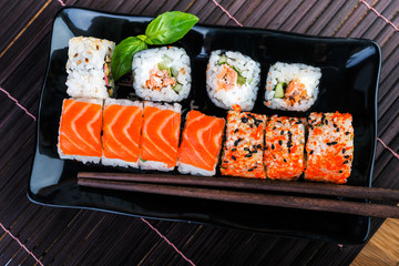  japanese food style.   sushi rolls assortment on black plate and chopsticks. Traditional  rolls on the dish.