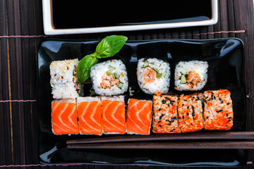sushi rolls assortment on black plate and chopsticks. Traditional  rolls on the dish.