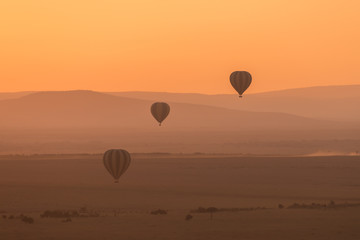 Three striped balloons fly over purple hills