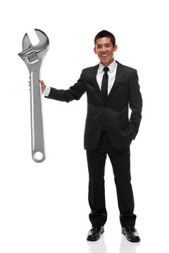 Businessman holding a giant adjustable wrench to the side, busin