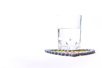Medicine pills or capsules heart shaped with glass of water