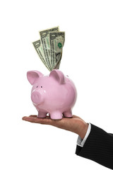 Businessman hand holding a piggy bank with money coming out of t