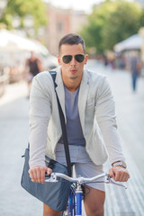 Handsome young businessman riding a bicycle and whistling