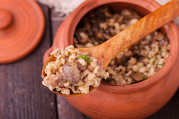 Barley porridge with mushrooms in a clay pot.selective focus