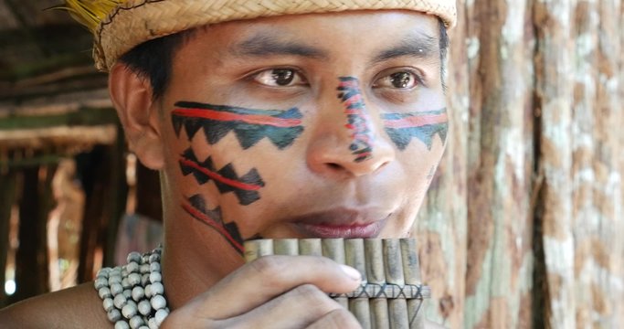 Native Brazilian playing wooden flute at an indigenous tribe in the Amazon