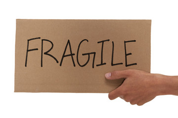 Hand holding up a cardboard fragile sign