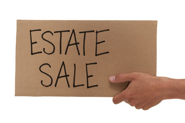 Hand holding up a cardboard estate sale sign