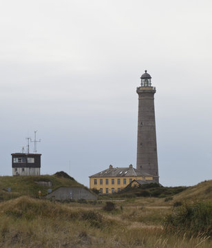The Grey Lighthouse. Taken on an overcast day, the backdrop sky to the grey lighthouse in the north of Denmark complements the sombre tone of the sand dune and buildings.