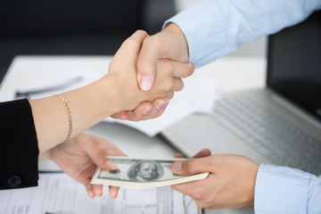 Fototapeta premium Woman and man handshake close up with the money in the other han