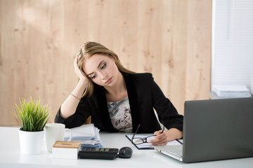 Tired business woman sitting at her working place