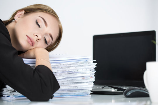 Tired business woman slleeping on heap of papers at her working