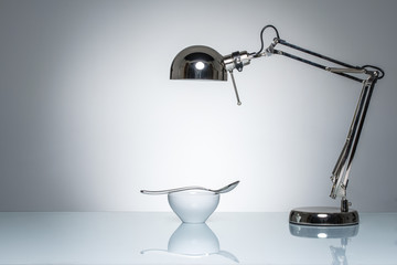 lighting up white ceramic bowl silver spoon with desk lamp