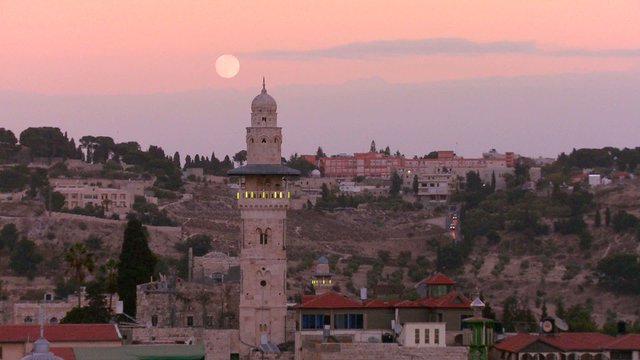 A time lapse view over the city skyline of the old city of Jerusalem with the moon rising.