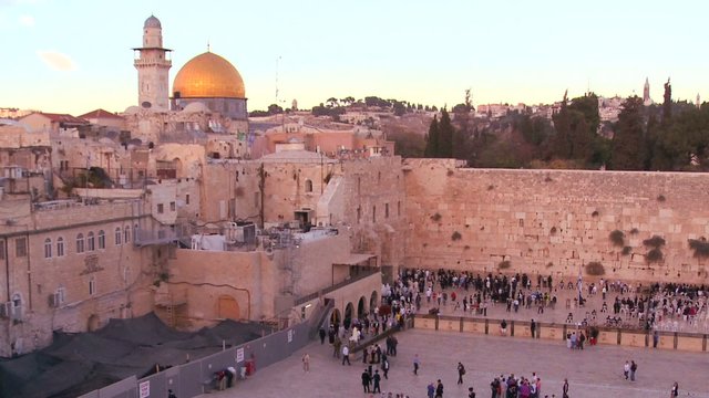 Fast motion of people beneath The Dome of the Rock as it towers over the Old City of Jerusalem and the Wailing Wall.
