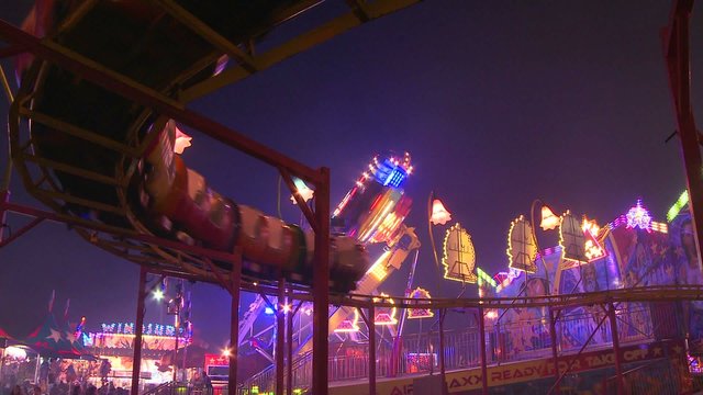 A small roller coaster at an amusement park, carnival or state fair at night. 