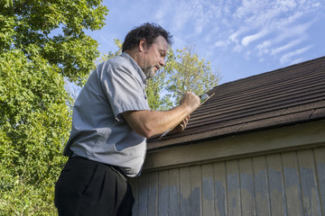 Insurance Adjuster Figuring Hail Damage To Roof