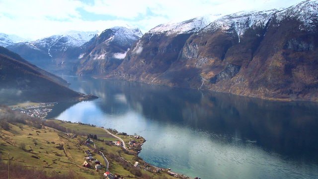 Tranquil and peaceful high panning shot of the fjords of Norway with hills foreground.