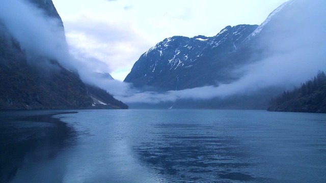Incredible clouds and fog hang over a fjord in Norway in timelapse.