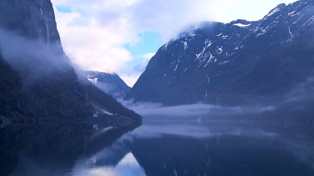 Clouds and fog hang over a fjord in Norway in timelapse.