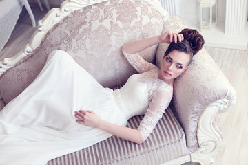 Young gorgeous bride is lying in antique couch