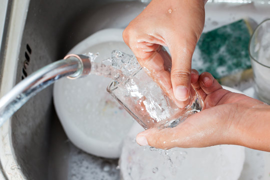 Woman hand washing  glass over the sink in the kitchen