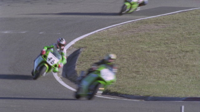 Motorcycles race on a circuit track.
