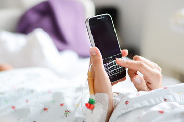 patient browsing a smartphone or mobile device in a hospital bed © adrian_ilie825