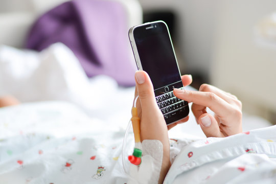 Patient Browsing A Smartphone Or Mobile Device In A Hospital Bed