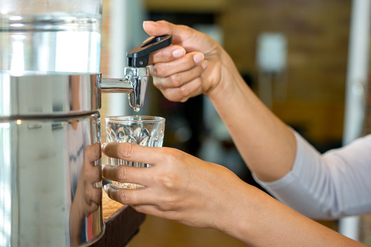 Woman hand pouring water in to clear glass