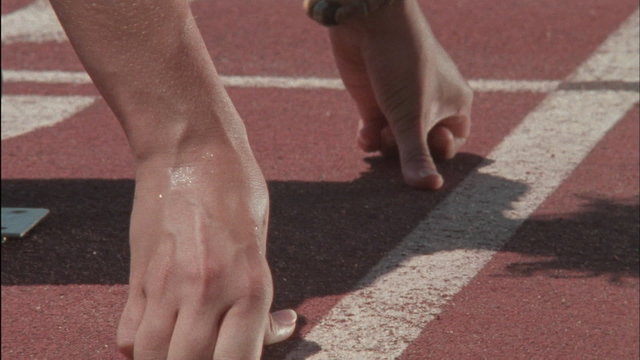 A runner kneels at the starting line, then starts racing.