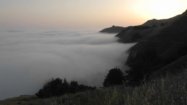 Time lapse of sun setting over fog rolling against the mountains at Big Sur, California.