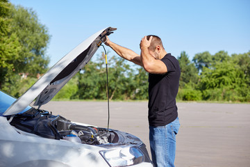 Young man standing in front of a broken car