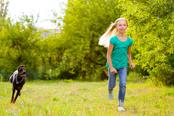 girl running away from dog or doberman in summer park