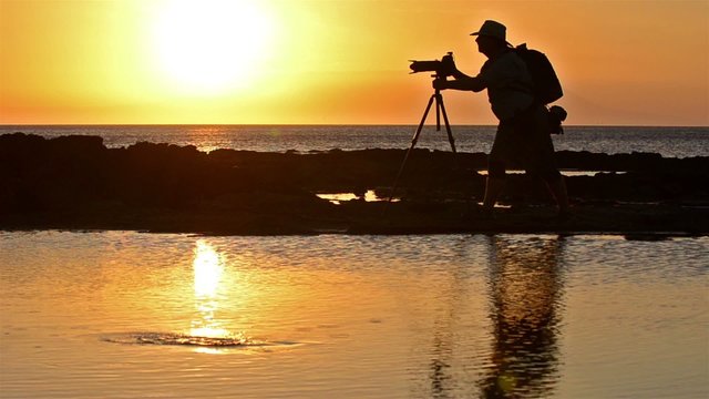 Photographers silhouette and sunset at Puerto Egas on Santiago Island in the Galapagos Islands National Park and Marine Reserve, Ecuador.