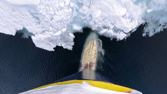 Tilt up bulbous bow point of view of an icebreaker ship plowing through sea ice in Hinlopen Strait in Svalbard Archipelago, Norway.