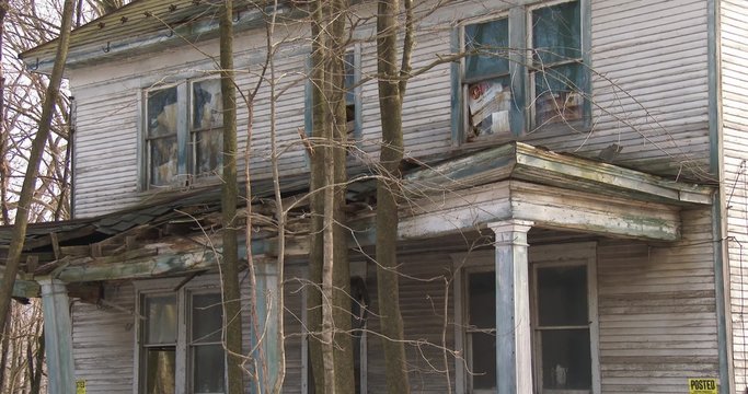 An abandoned and lonely farmhouse is rotting and overgrown.