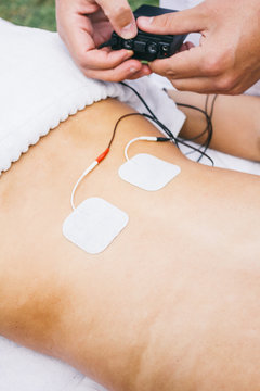 Physiotherapist using electrodes on the back of a patient