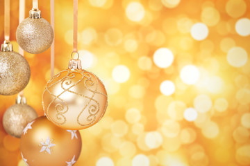 Gold Christmas baubles hanging in front of a gold background - Powered by Adobe
