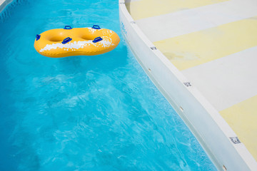 Yellow rubber ring floating on refreshing blue water