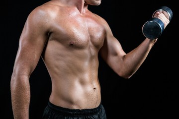 Fototapeta na wymiar Midsection of shirtless athlete working out with dumbbell