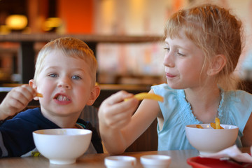 Children in cafe eat potato
