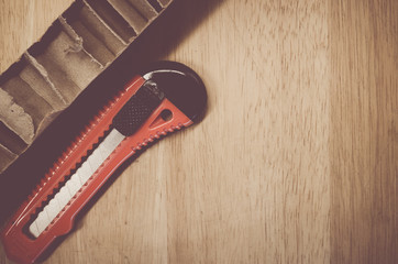 packaging cardboard sections and cutter on a wood surface