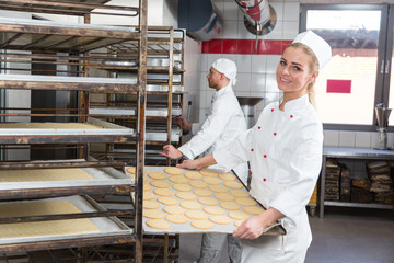 Baker presenting tray with pastry or dough at bakery