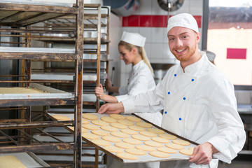 Fototapeta na wymiar Baker presenting tray with pastry or dough at bakery