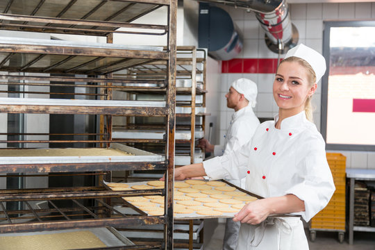 Baker presenting tray with pastry or dough at bakery