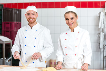 Instructor and apprentice in bakery making pretzels