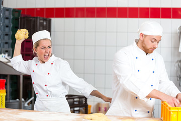 Baker who is frustrated with collegue throwing dough at him